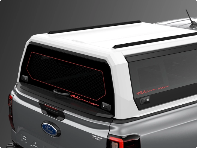 Rear view of a grey Ford Ranger pickup truck fitted with a white canopy (truck cap) featuring "Rhino-Rack" branding and a red-outlined mesh window.