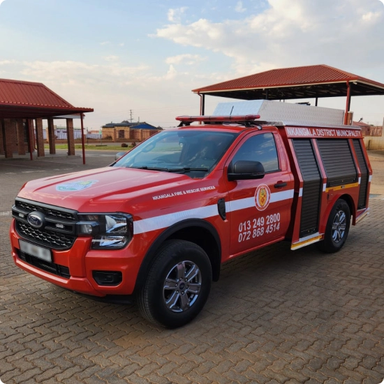 A red Ford Ranger pickup truck, modified as a fire and rescue vehicle with a utility body, light bar, and "NKANGALA FIRE & RESCUE SERVICES" markings, is parked on a paved area.