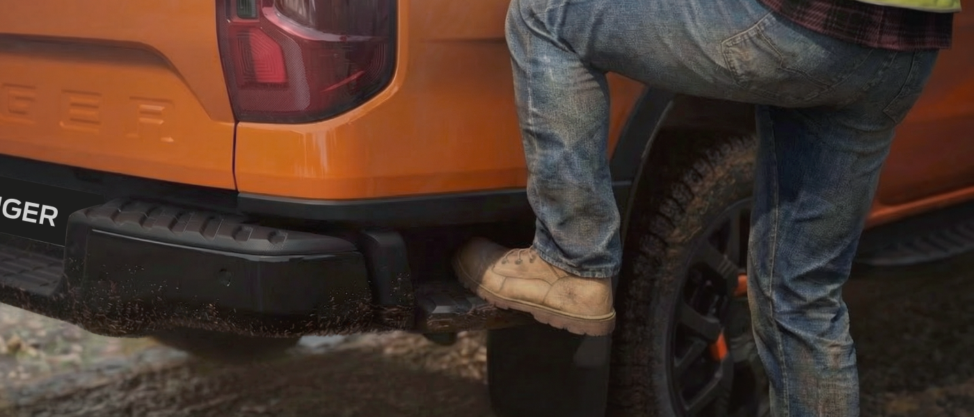 A person stepping onto a Ford Ranger's rear bumper