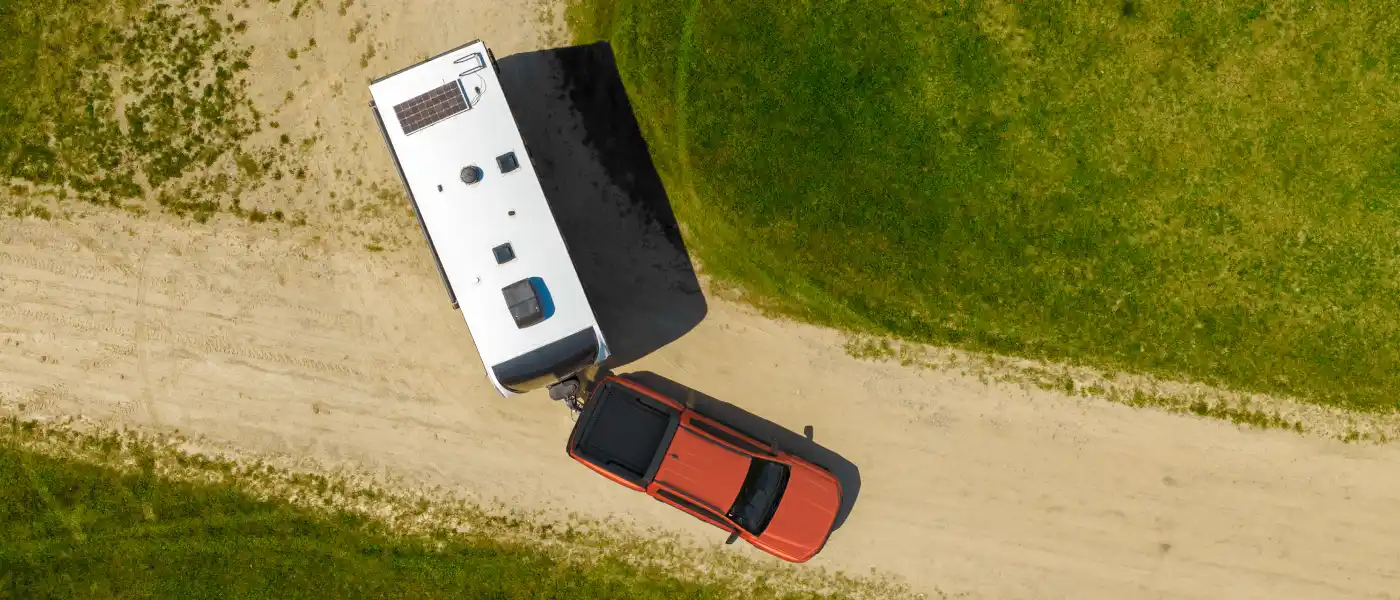 Aerial view of pickup truck towing caravan on dirt road.