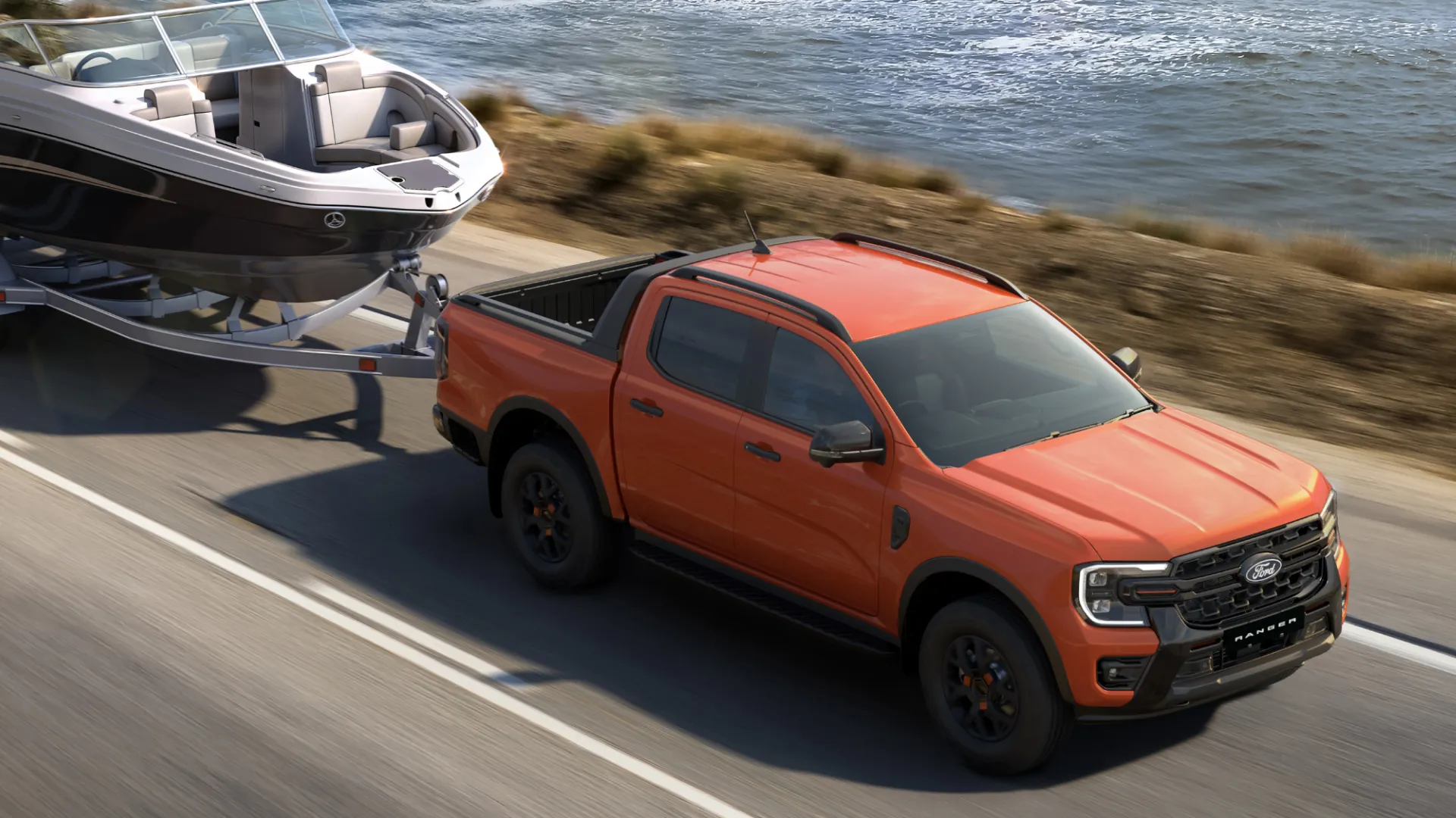 Ford Ranger towing boat on highway near water.
