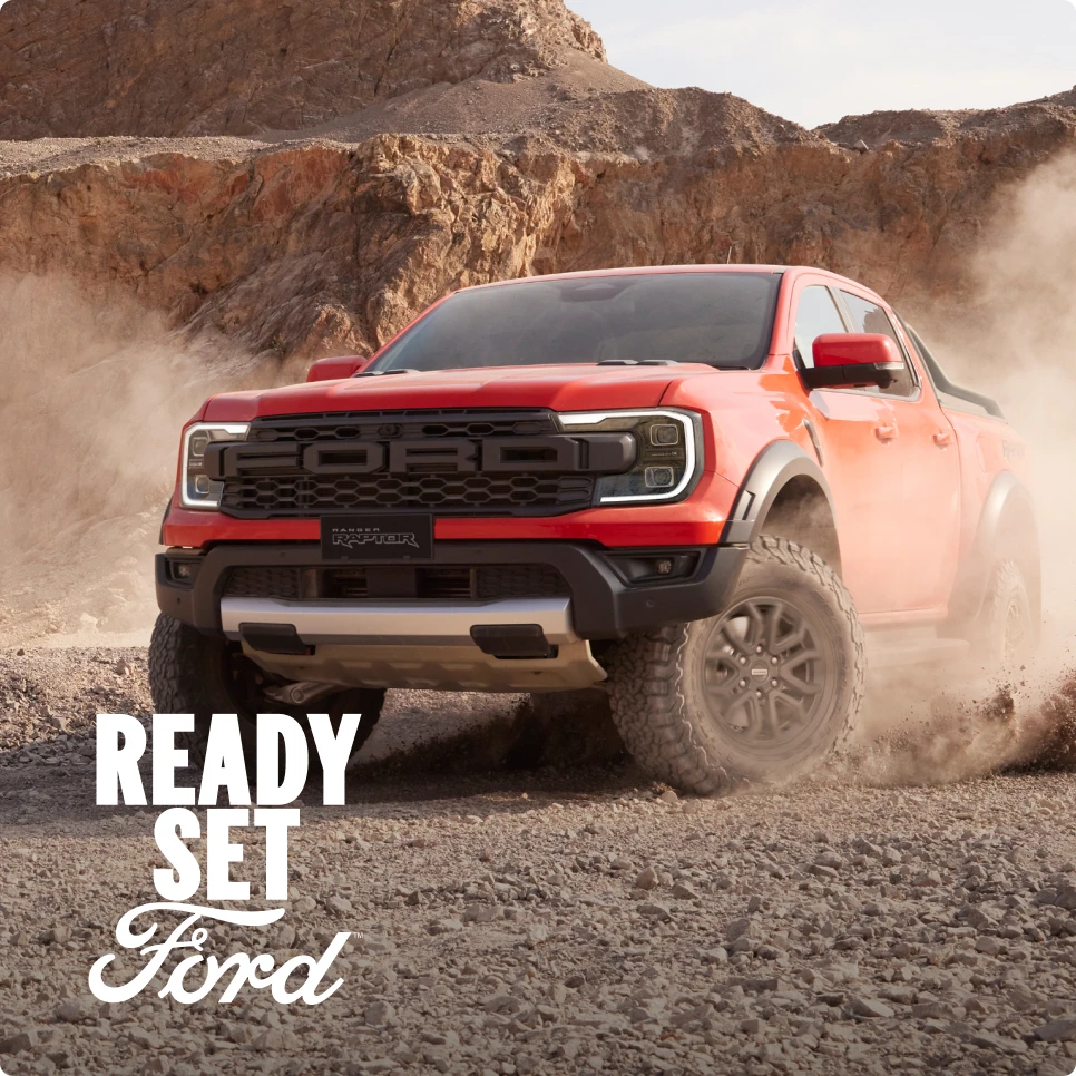 Red Ford pickup driving on rocky terrain with Ready Set Ford text.