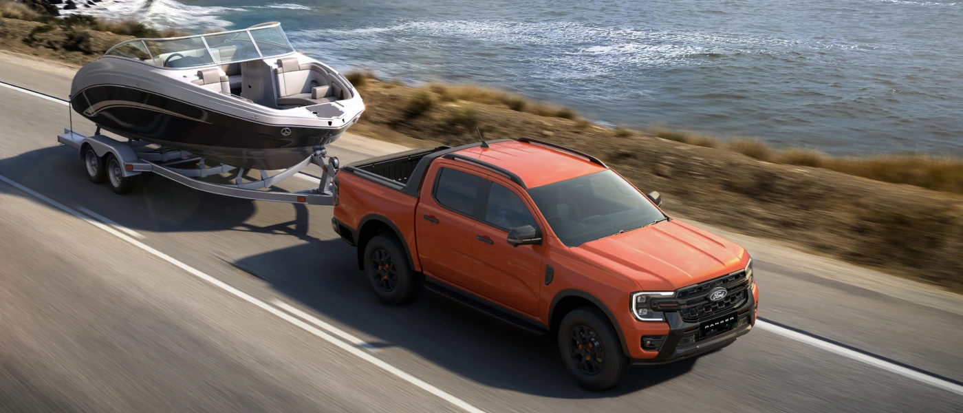 Pickup truck towing a caravan on a dirt road aerial view