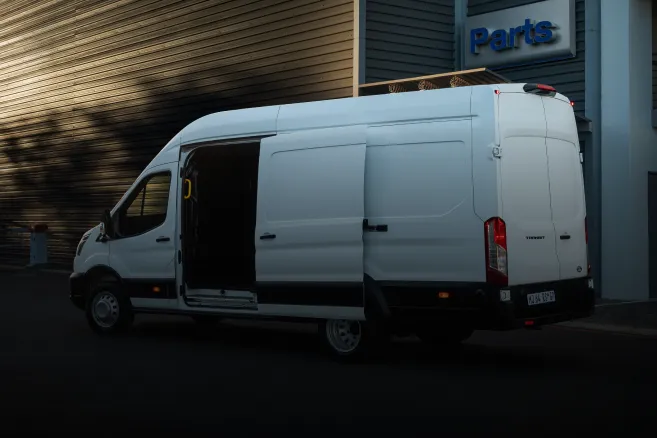 White Ford Transit van with open side door outside parts center