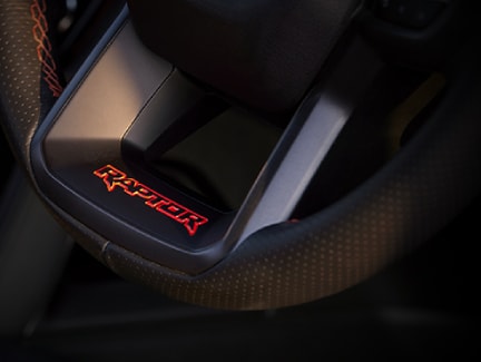 Steering wheel with "Raptor" logo and "Code Orange" stitching